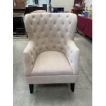 An upholstered armchair with buttoned back