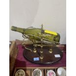 A brass wine bottle stand/pourer on wood base