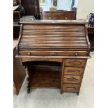 A 1930s oak roll-top desk, the tambour shutter over a flight of four drawers and recess. 36' wide