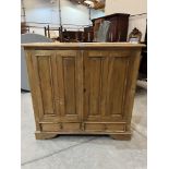 A pine cupboard enclosed by a pair of folding doors over conforming base drawers. 48' w x 47'h