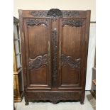 A 19th century French joined oak armoire, carved with trailing foliage, enclosed by a pair of