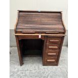 A 1930s oak roll-top desk enclosed by a tambour shutter over four drawers. 36' wide