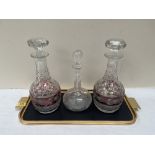 Three cut glass decanters and a metal tray