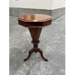 A Victorian walnut trumpet work table with octagonal top on facetted tapered well and tripod