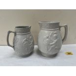 A pair of salt glazed jugs, each moulded with putti riding fish. The larger jug 7' high. 19th