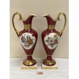 A pair of Lindner ewers, painted with summer flowers in two reserves on a burgundy ground and