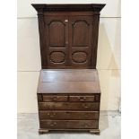 An 18th century joined oak bureau cupboard enclosed by a pair of geometrically fielded doors over