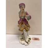 A Derby figure of a lady in brightly coloured clothes and gilded skirt. Crown mark over crossed