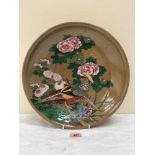 A Japanese glazed pottery charger, painted with birds, chrysanthemums and foliage on a buff