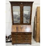 An 18th century walnut bureau bookcase, enclosed by a pair of mirrored doors over a pair of candle