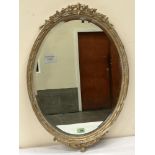An early 20th century oval gilt gesso wall mirror with bevelled plate. 29' high