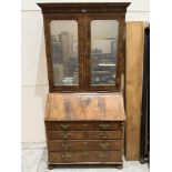 An 18th century walnut bureau bookcase, enclosed by a pair of mirrored doors over a pair of candle