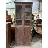An early 20th century decorated pine cupboard enclosed by a pair of glazed doors over a pair of