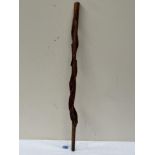 An African treen stick, sinuously carved with a serpent and leafy foliage. 35' long