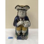 A late 18th century / early 19th century pearlware Toby jug, the character holding a pitcher and