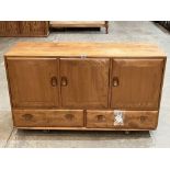 An Ercol sideboard enclosed by three doors over a pair of drawers. 51' wide. Replacement handles