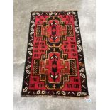 A Balochi red ground rug. 1.41m x 0.86m