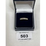 A seven stone diamond channel set ring. In gold marked 18KT. 3.2g gross. Size L
