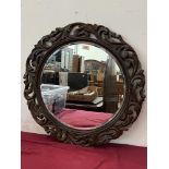 A carved oak framed wall mirror. 27' diam
