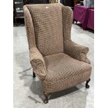 A 1920s upholstered wing armchair on cabriole legs