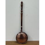 An early 19the century copper warming pan with turned fruitwood handle, the lid wriggle-work