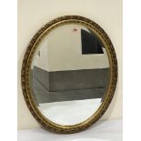 A gilt oval wall mirror with bevelled plate. 22½' high