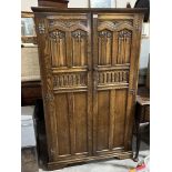 An oak wardrobe enclosed by a pair of linenfold and vine fruit carved doors. 39' wide