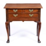 A George II walnut lowboy, with oversailing moulded top and fitted with an arrangement of three