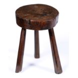 A primitive oak stool, 19th c, on three chamfered legs, 49cm h Provenance: E M Cheshire,