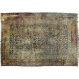 An antique Kerman carpet, with dark blue ground, 394 x 558cm Worn and holed, stained / dirty but