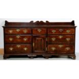 A George III oak dresser, late 18th c, the moulded top with low swan neck upstand, fitted with an