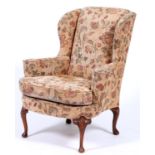 A George II style mahogany framed wingback armchair, upholstered in modern floral design fabric,