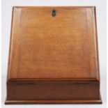 An Edwardian oak slope front stationery box, with fitted interior and pair of brass capped inkwells,