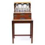 An Edwardian oak tantalus, mounted with EPNS escutcheon, strapwork and handles, mirror back and