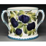 A Wemyss ware three handled loving cup, c1900, painted with plums, 18.5cm h, impressed and painted