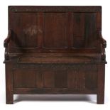 An oak settle, the three panel back with lunette carved crest rail, conforming box seat with