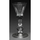 An English wine glass, c1710, the bell bowl with solid base with tear, on baluster stem with tear,