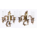 A pair of French revived rococo gilt brass wall lights, early 20th c, the three leafy scrolling