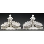 A pair of Continental glazed porcelain child figural double basket sweetmeat stands, late 19th c,
