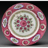 An Islamic glazed earthenware plate, probably 19th c, painted with flowers in raspberry red, green