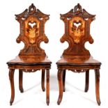 A pair of Swiss carved, inlaid and etched walnut musical hall chairs, c1900, crested by an eagle,