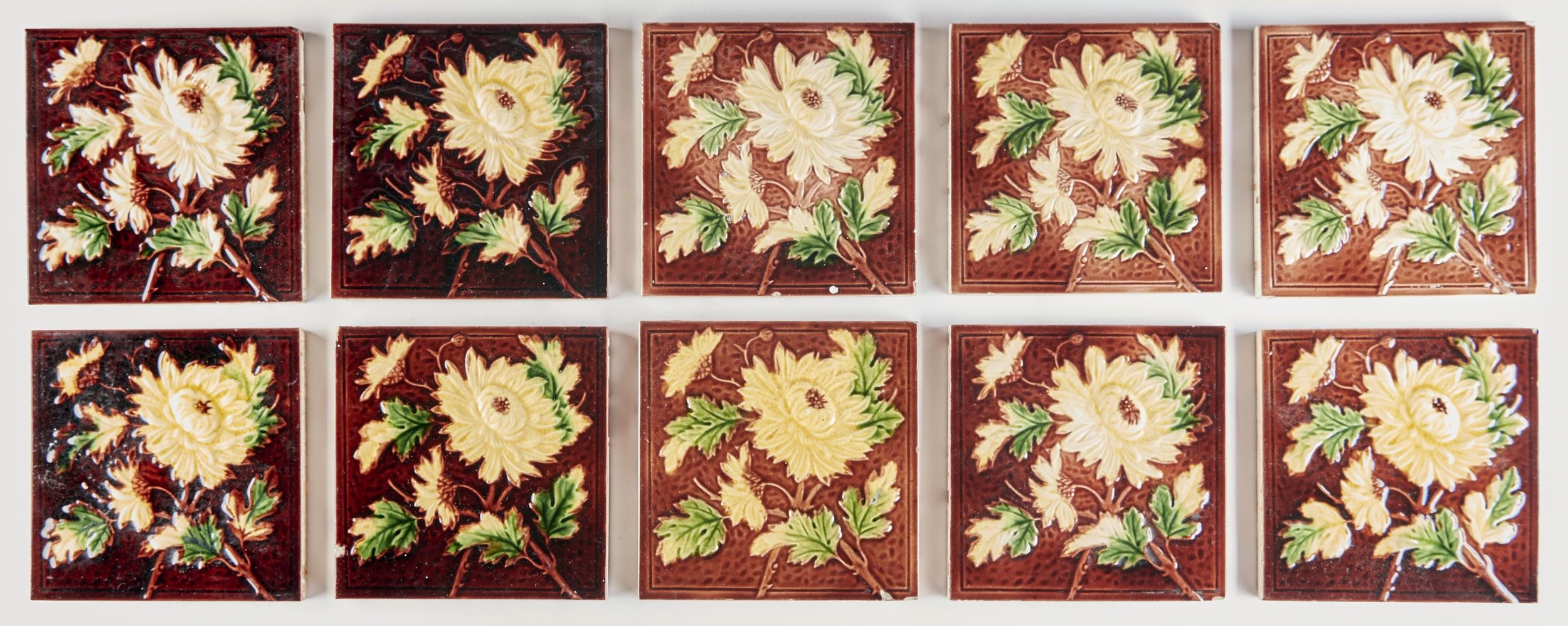 A set of ten late Victorian 6" majolica wall tiles, c1890, moulded with flowers and leafage on a
