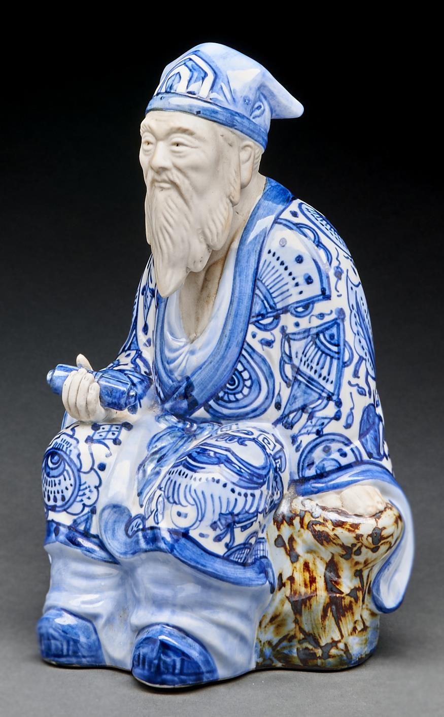 A Japanese biscuit and blue and white and aubergine glazed figure of a sage, 31cm h, circular