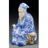 A Japanese biscuit and blue and white and aubergine glazed figure of a sage, 31cm h, circular