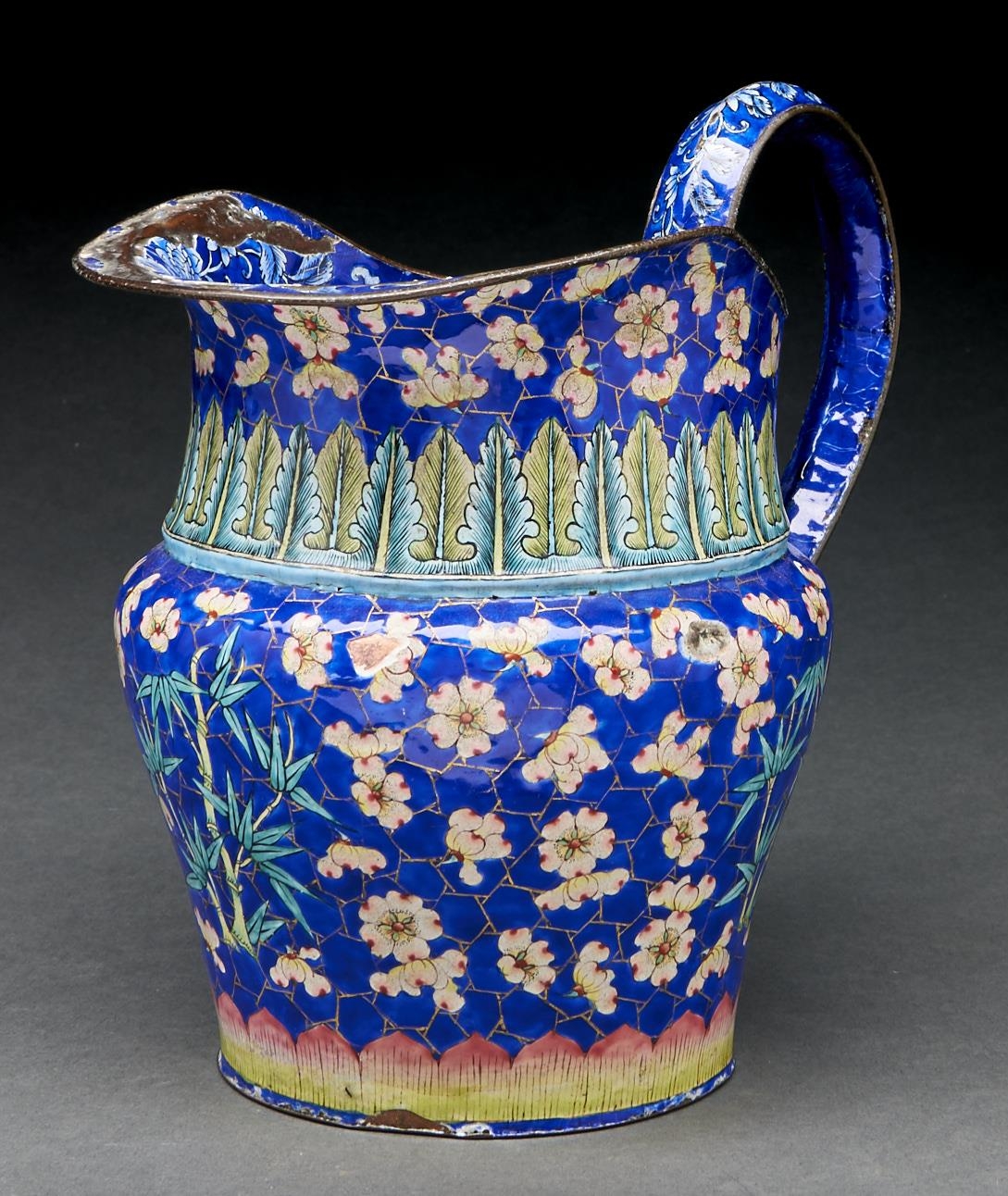 A Canton painted enamel jug, 19th c, decorated in two registers with blossom and bamboo on a blue