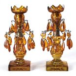 A pair of brass mounted amber flashed and cut glass lustre candlesticks, early 20th c, hung with two