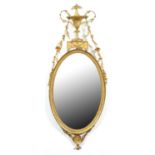 A George III neo classical giltwood and composition mirror, the oval frame surmounted by an urn on a