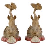 A pair of cast brass dolphin appliques, later mounted on carved wood as door stops, painted gold,