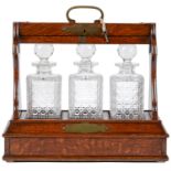 A Victorian brass mounted oak tantalus, with three decanters, of conventional form, the Bramah