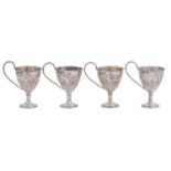 A set of four Victorian silver handled egg cups, chased with flowers beneath crimped rim, 75mm h, by
